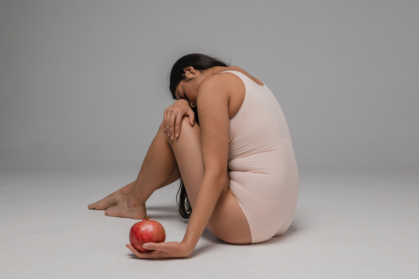 Woman in Nude Shapewear Holding a Pomegranate